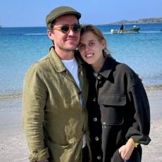 Princess Beatrice and Edoardo Mapelli Mozzi wearing green jackets on the beach and smiling