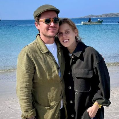 Princess Beatrice and Edoardo Mapelli Mozzi wearing green jackets on the beach and smiling