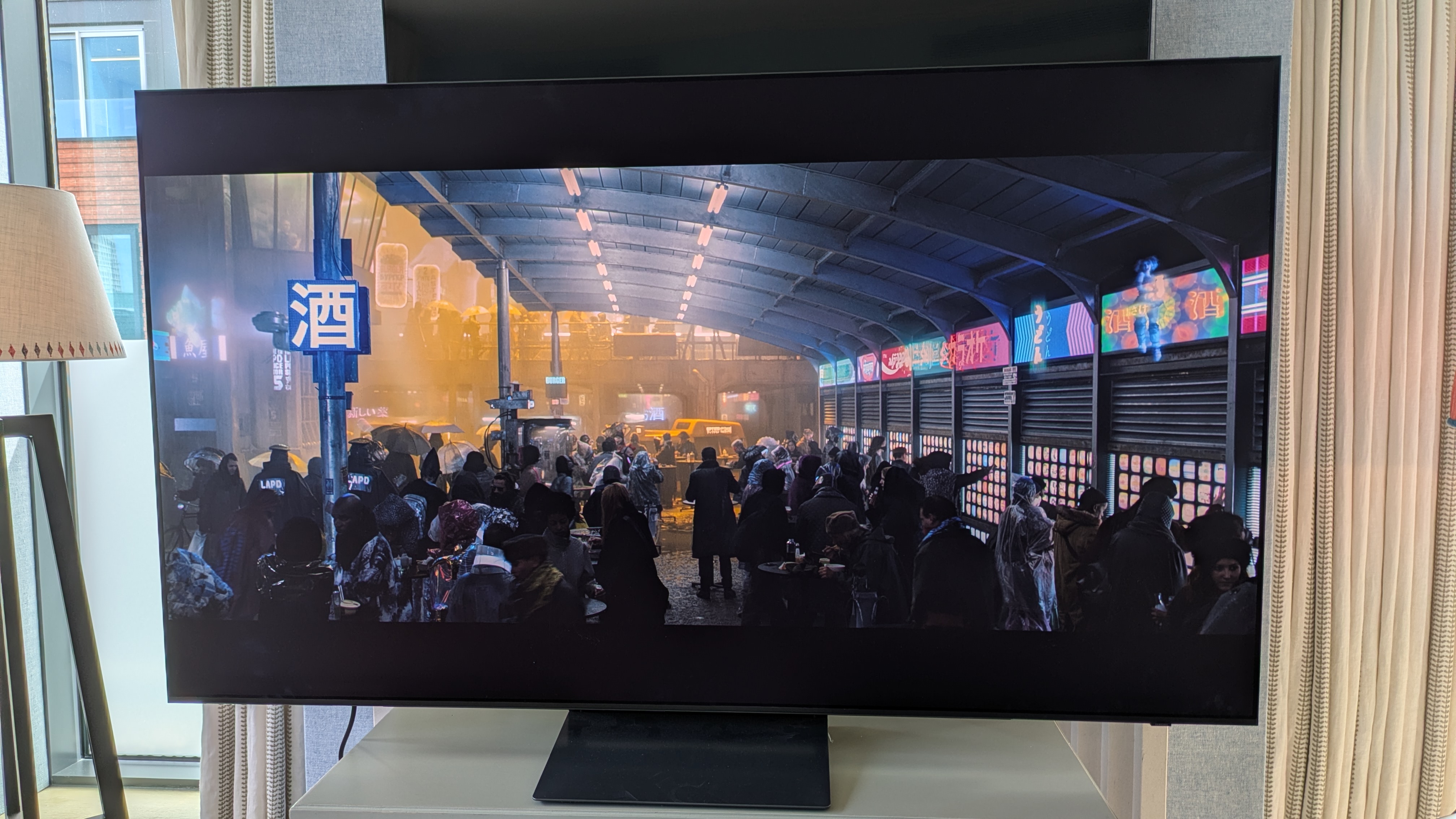 Samsung S90H OLED TV with night market scene from Blade Runner: 2049 on screen