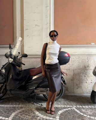 @sylviemus_ wears a leather skirt with heels.