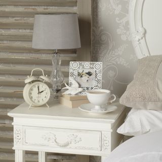White bedside table with alarm clock and lamp