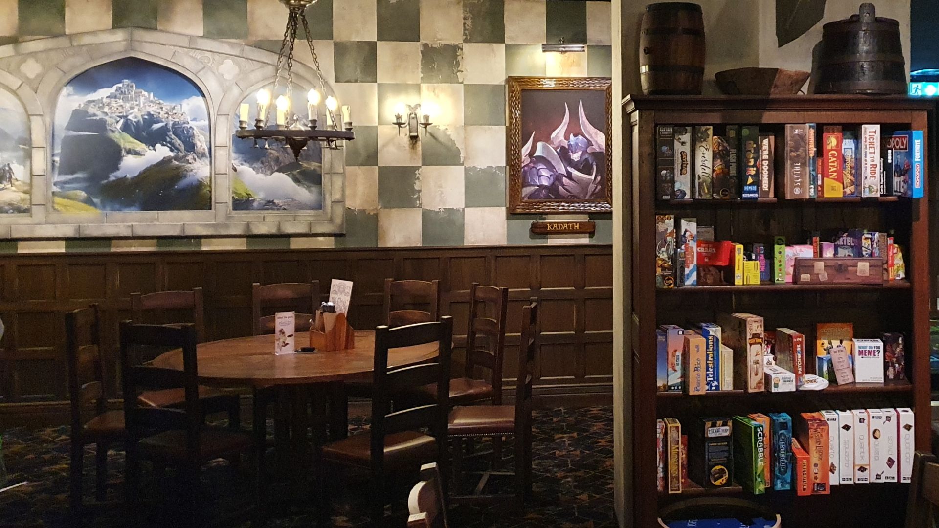 A shelf of board games next to a table and chairs