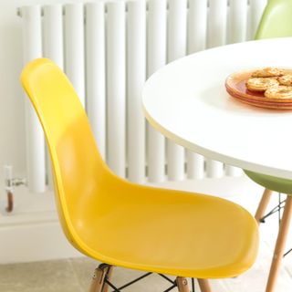 room with white round table with orange plates and yellow chair