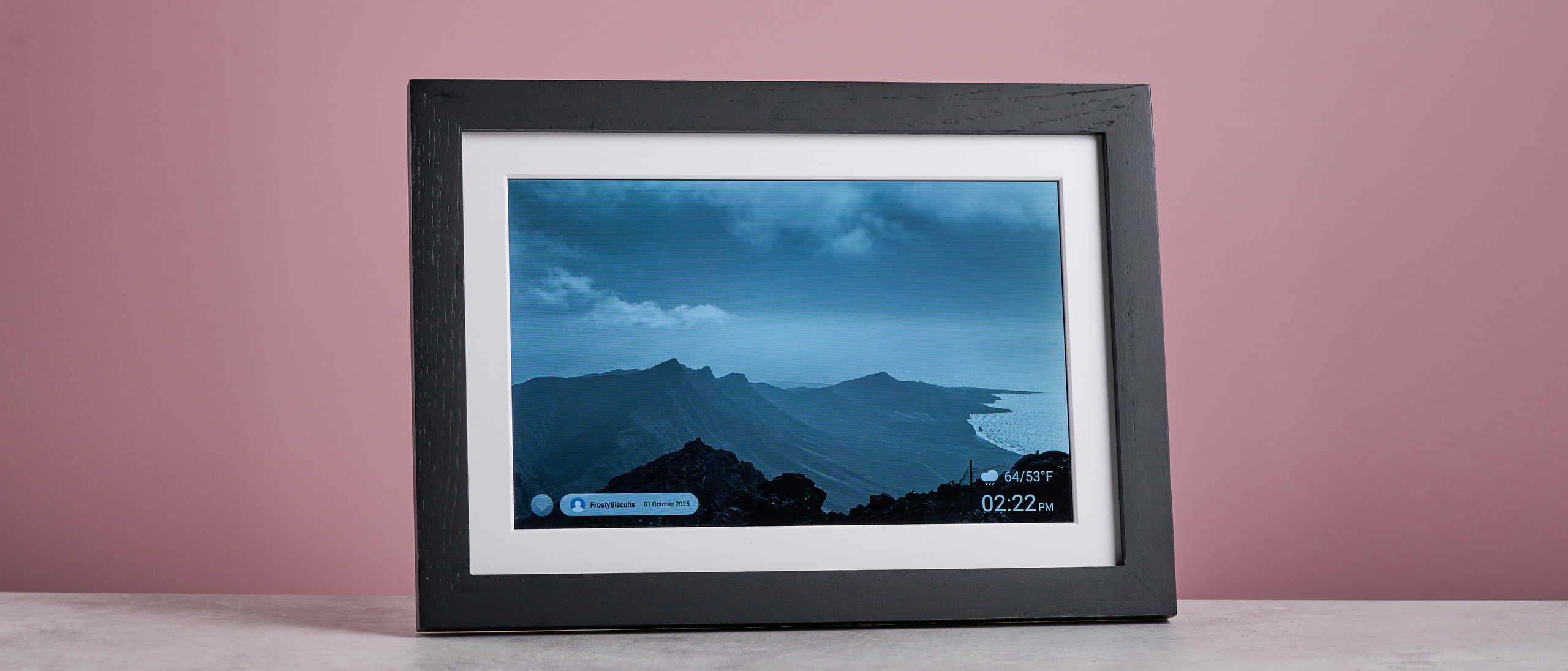 The Eptusmey 10.1-inch WiFi Digital Photo Frame in horizontal orientation, showing a black and white photo of mountains and sea in the Canary Islands.
