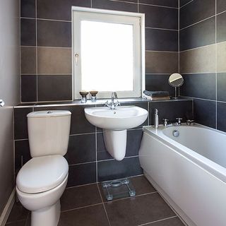 bathroom with tiles wall and bathtub and washbasin and toilet