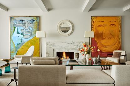 A living room with a marble fireplace and art work on the walls