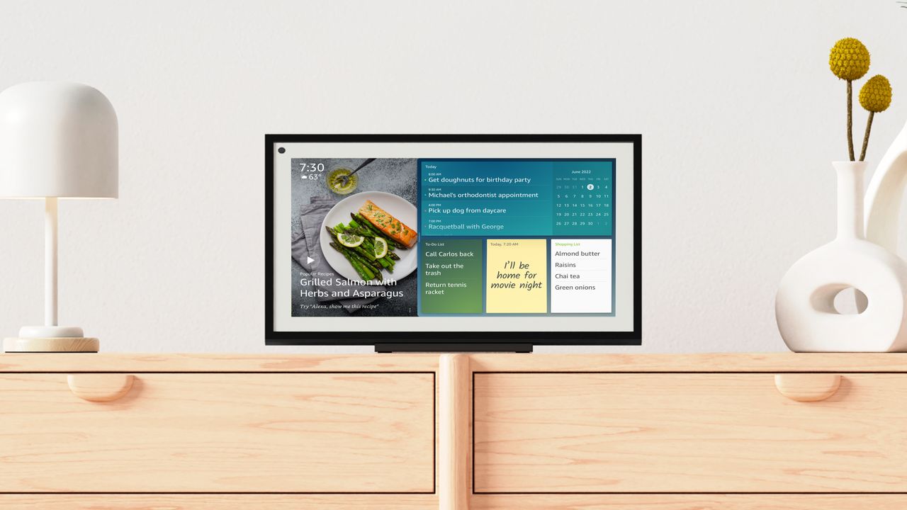 An Amazon Echo Show 15 on a side cabinet displaying a home screen