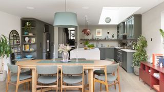 open plan kitchen diner with oval wooden dining table and large roof lantern