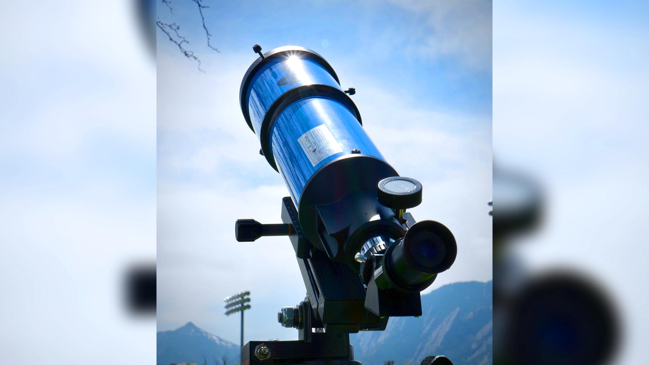 iOptron 80mm white light solar telescope set up for solar observing near a mountain range