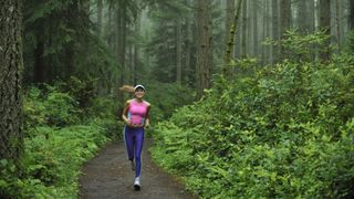 A woman running on a forested trail