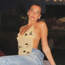Dua Lipa wearing a sheer halter top with baggy jeans and red Puma Speedcat sneakers at the Sunny Hill Festival July 2024