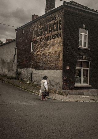 An individual walking past an older brick building