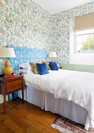 blackout blinds in bedroom with patterned wallpaper and white bed with blue patterned headboard