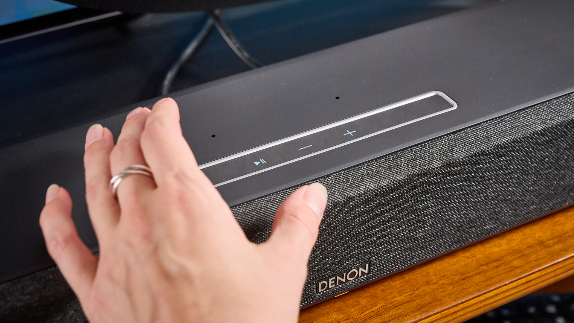 the denon home sound bar 550 with a gray mesh casing and touch controls for bluetooth on the top with a remote and smart home integration