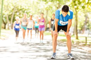 A tired runner in a race leaning on their knees