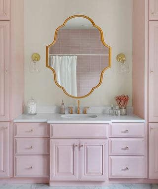Pale pink bathroom scheme with statement shaped gold wall mirror