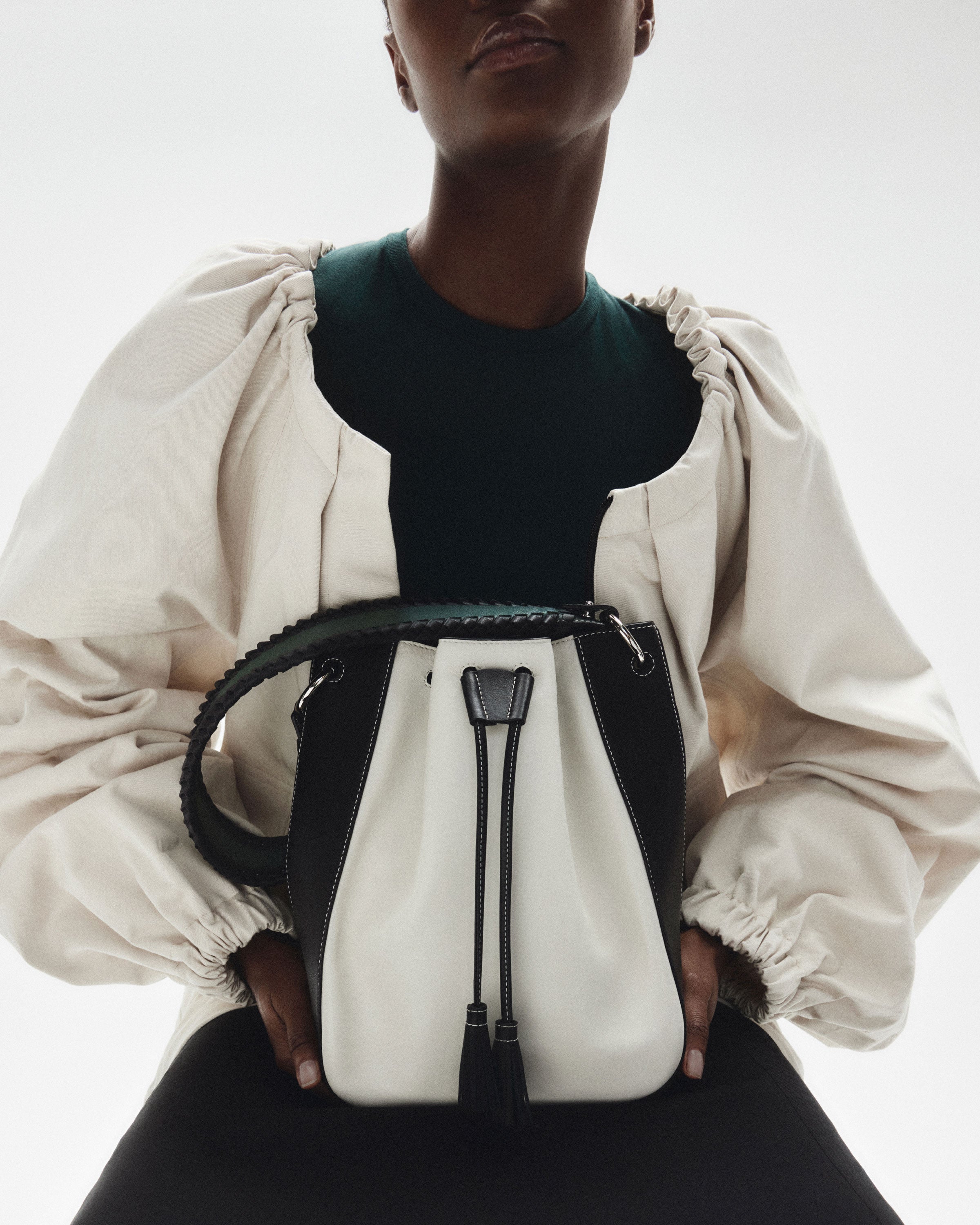 a model holds a black and white bucket bag