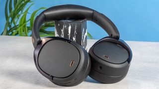 A pair of black Edifier WH950NB over-ear headphones photographed against a blue background