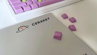 Close up of the box for a set of Cerakeys keycaps with loose keycaps on top and a keyboard in the background