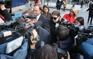 Belle Gibson surrounded by reporters while leaving court