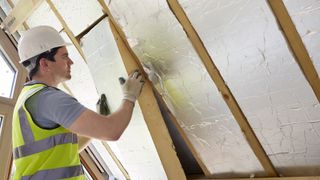 Ireland retrofit scheme begins - man insulating between roof rafters
