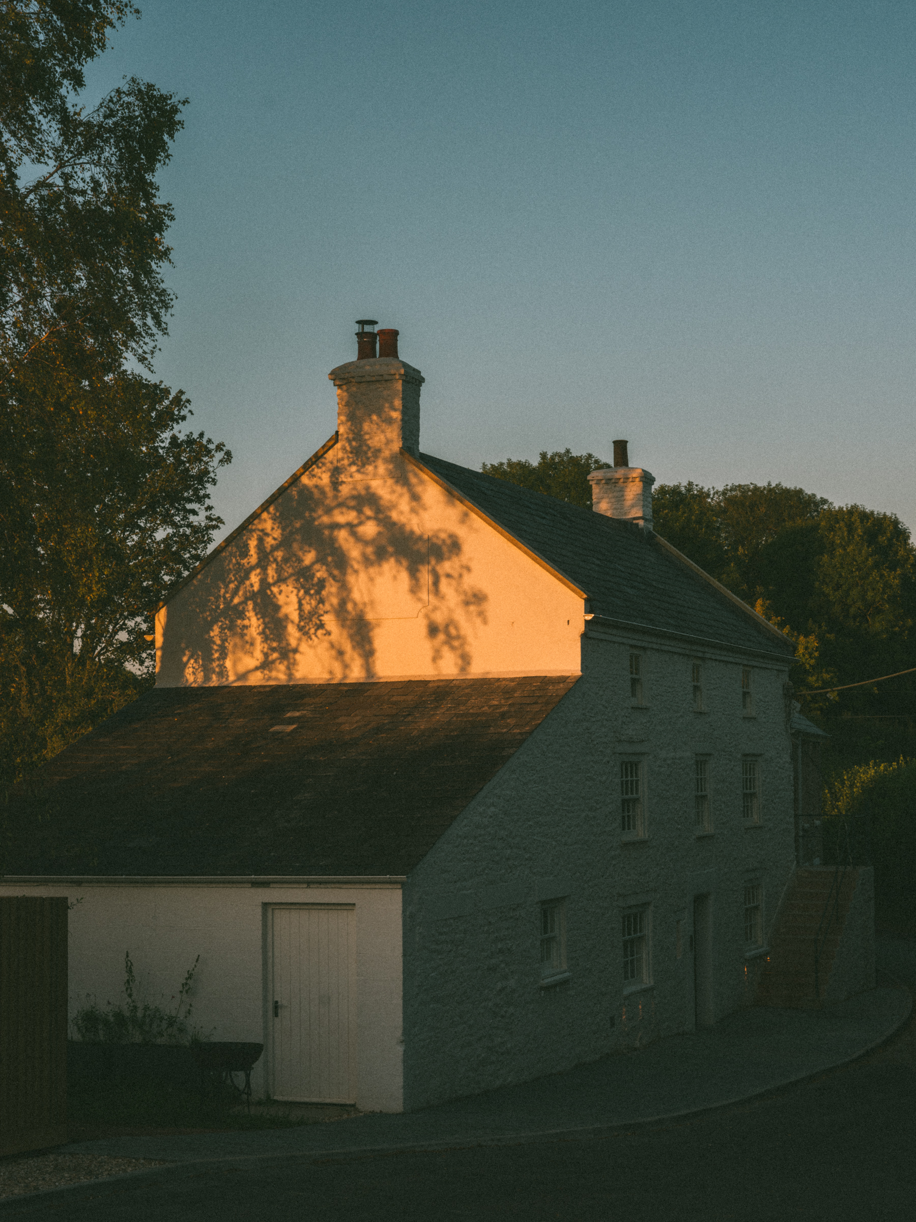 A series of shots depicting the interiors of a modernly renovated, old farmhouse in the countryside, mixing a rustic frame with plush textiles, textural surfaces, glass, wood, and chrome accents, and colorfully plated dishes.