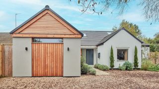modern house with rendered walls, garage with wooden door and gravel driveway