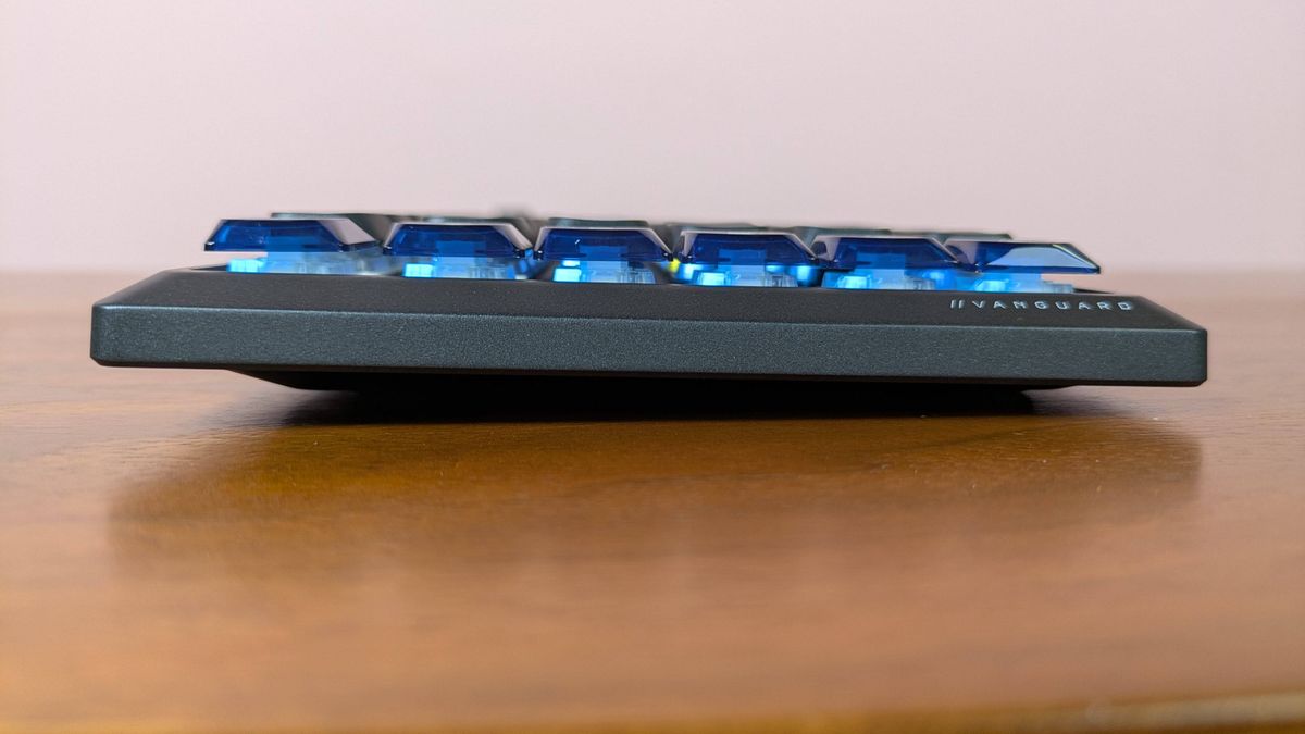 Side view of Corsair Vanguard Air 99 Wireless on brown desk with pink wall in background