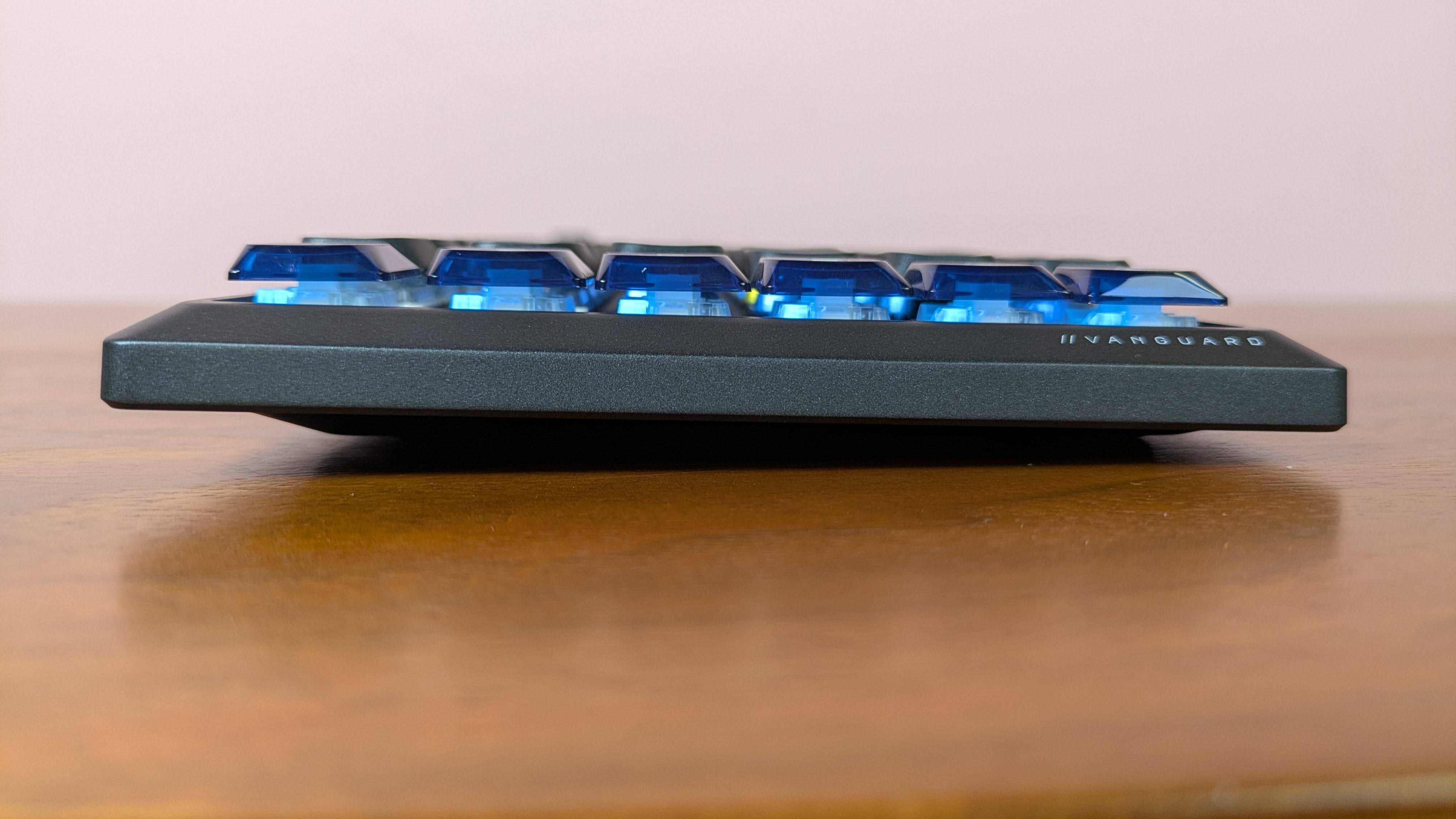 Side view of Corsair Vanguard Air 99 Wireless on brown desk with pink wall in background