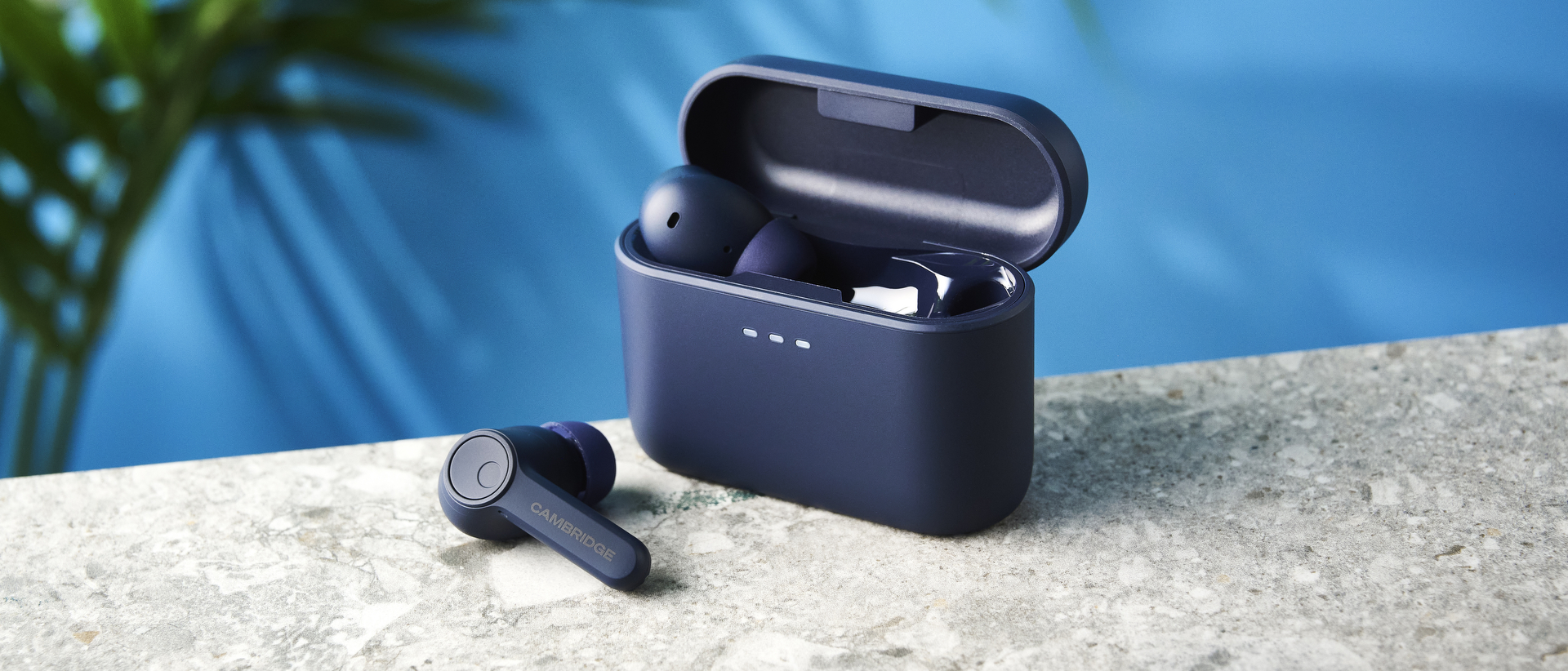 the cambridge audio a100 se earbuds on a blue tom's guide background with a stone-coloured table underneath