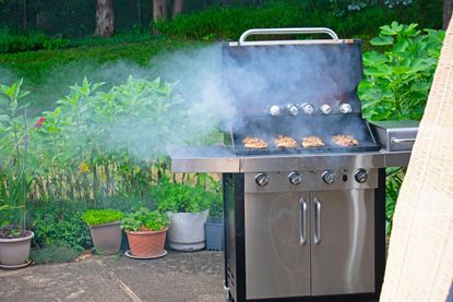 An example of when is it antisocial to grill - a smoky grill cooking chicken in a backyard