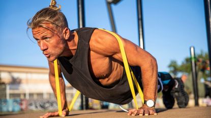 A man performing a resistance band push-up as part of a full-body strength training workout 