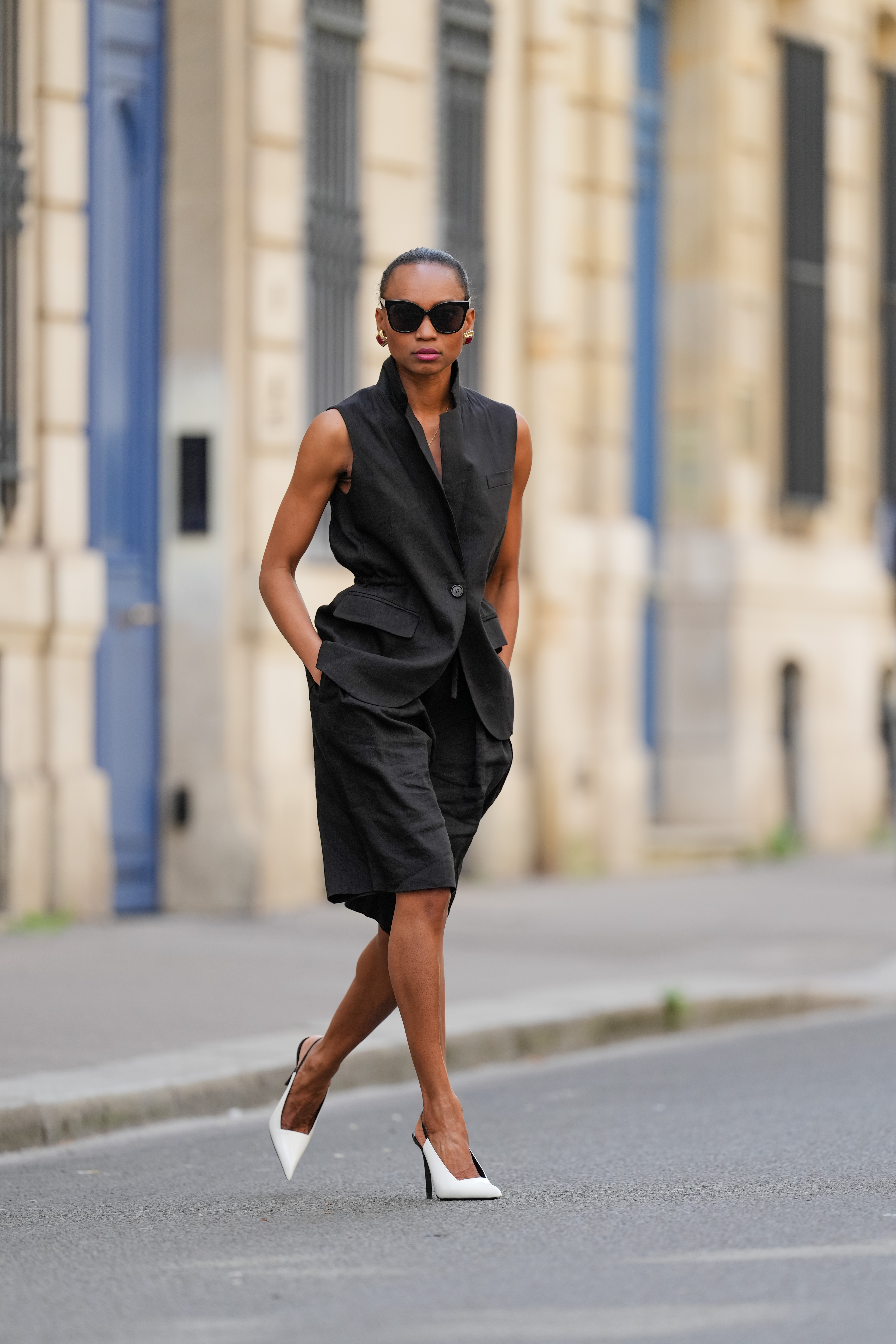 woman wearing black vest, black bermuda shorts and white heels