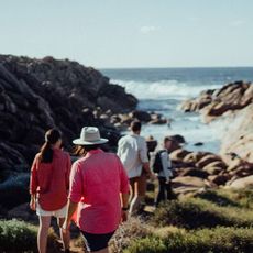 A family walking along a sunny, rocky beach.