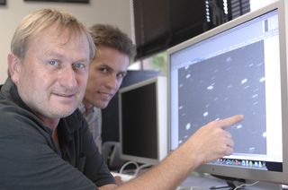 Richard Wainscoat (left) and Marco Micheli study one of the near-Earth asteroids found on Jan. 29, 2011, using the Pan-STARRs PS1 telelescope in Hawaii. The asteroid is the roundish dot near Wainscoat’s finger.