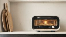 Black pizza oven on white countertop next to three wooden cutting boards