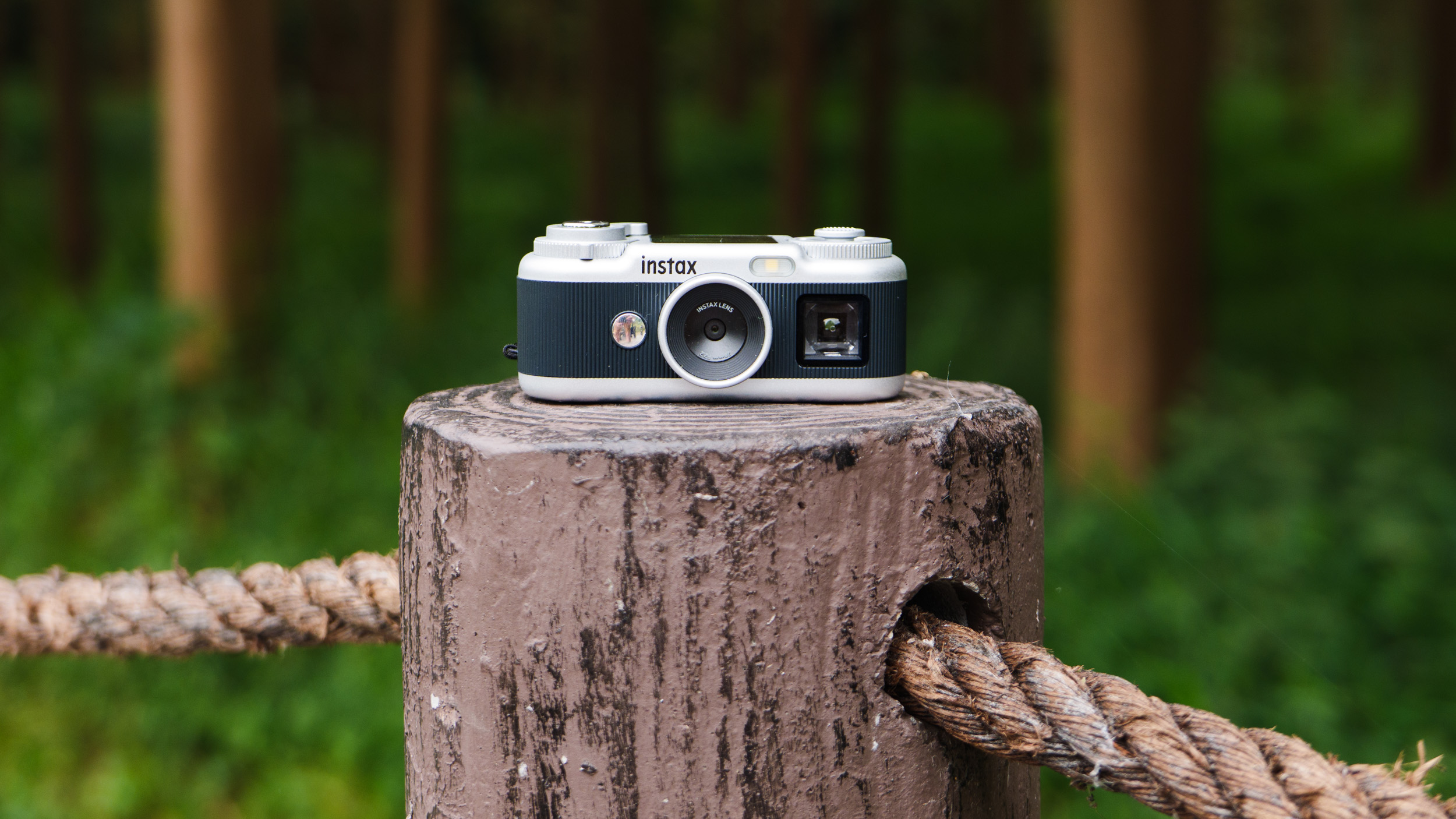 Fujifilm Instax Pal 2 digital camera on a wooden post next to a forest