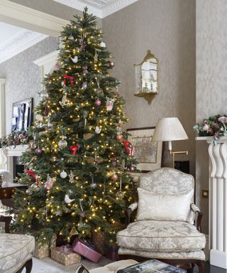 Christmas tree themes 2021 with a traditional scheme of gold and silver baubles and miscellanous character decorations in a traditional living room
