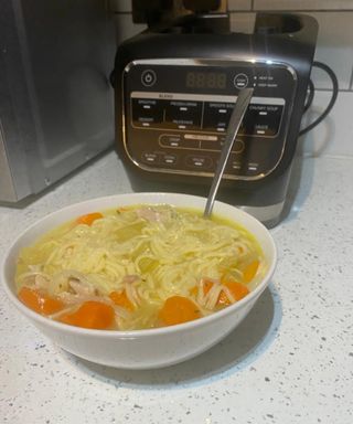 A bowl of chicken noodle soup with Ninja Cold and Hot Blender in background