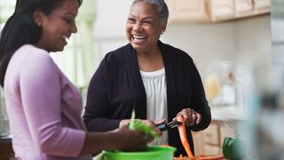 Health benefits of carrots: an older woman preparing carrots - which have anti-inflammatory properties - in the kitchen with her daughter