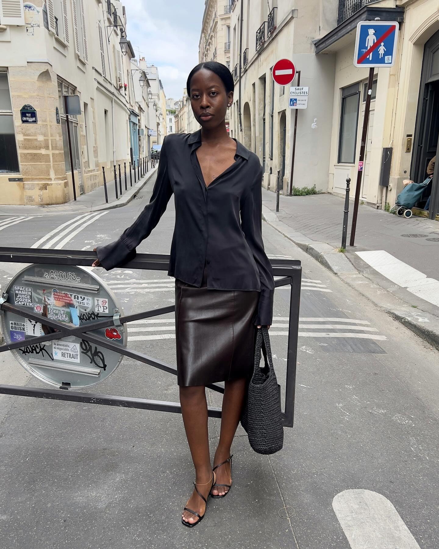 @sylviemus_ wearing a black blouse and a leather skirt.