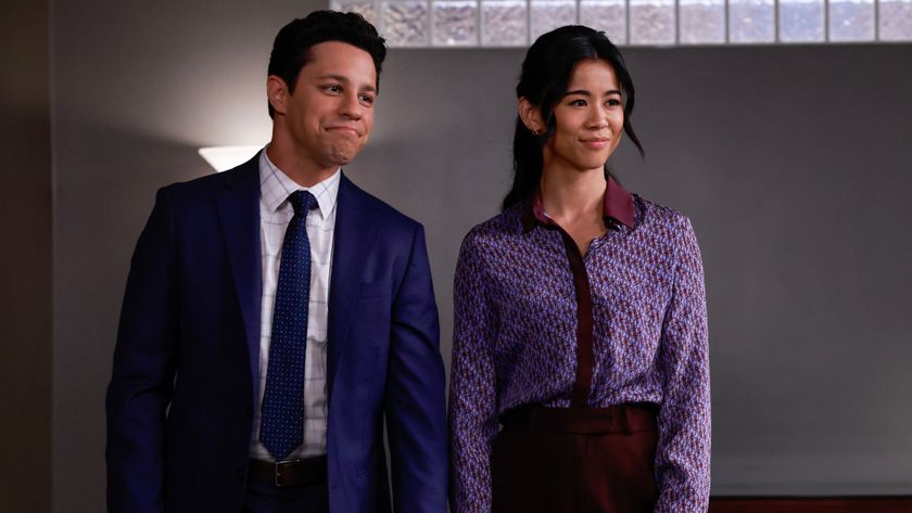 David Del Rio and Leah Lewis stand together smiling in an office in Matlock S1 E18 - &quot;Tricks of the Trade, Parts 1 and 2.&quot;