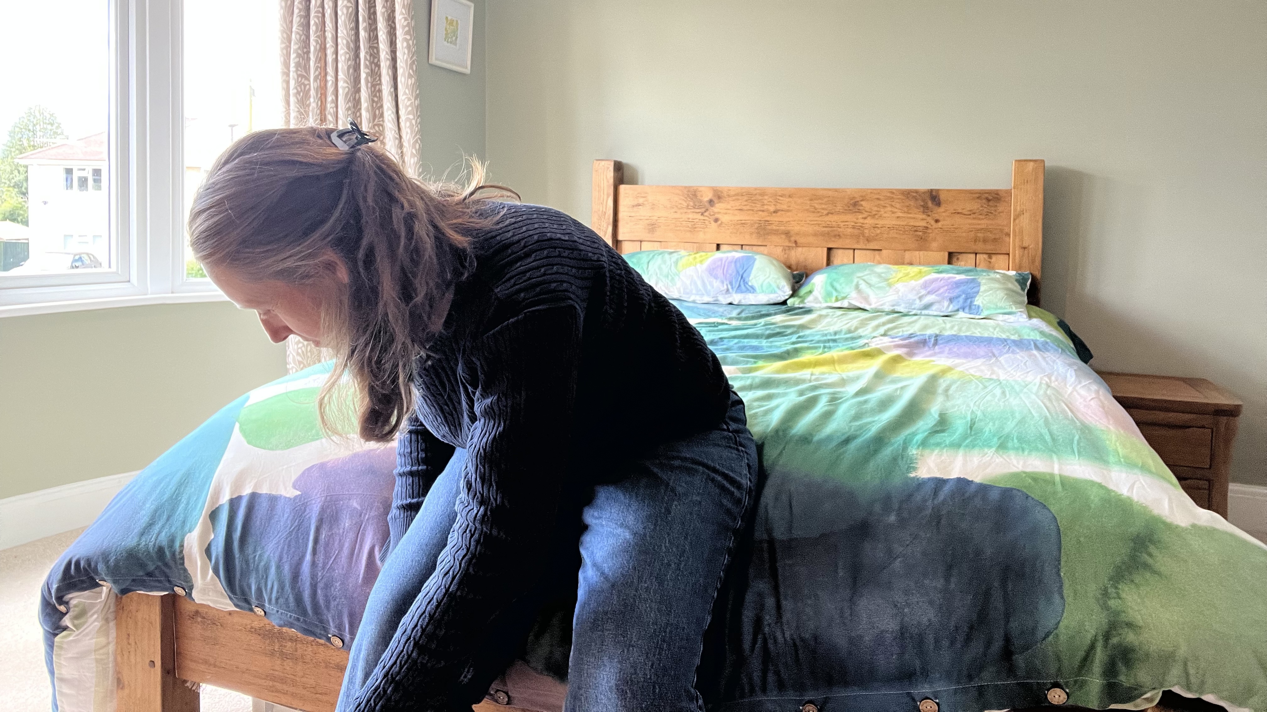 reviewer sitting on the edge of the nectar classic hybrid with bedding