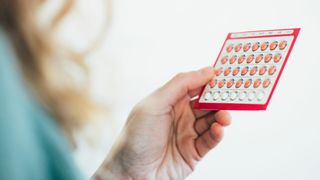 close up of a hand holding package of contraceptive pills