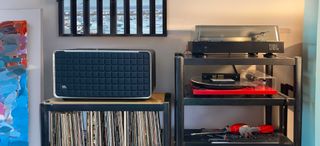 JBL Spinner BT on a hi-fi rack shelf next to records and speakers