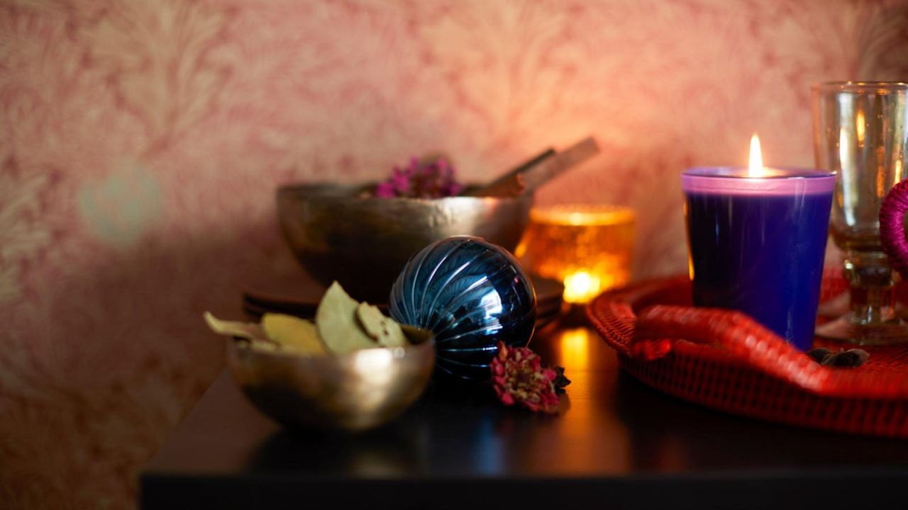 Christmas candles, a bowl of bay leaves, and other Christmas scents set out alongside some baubles on a dresser