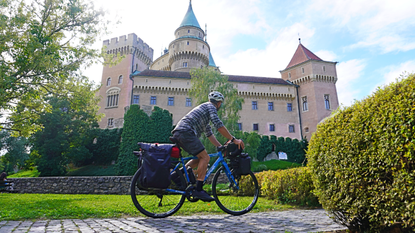 Image shows a person riding a bike with pannier bags attached