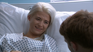 Lola Pearce smiling wearing a hospital gown with Jay Brown