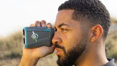 A golfer looks for a yardage using a Bushnell laser rangefinder