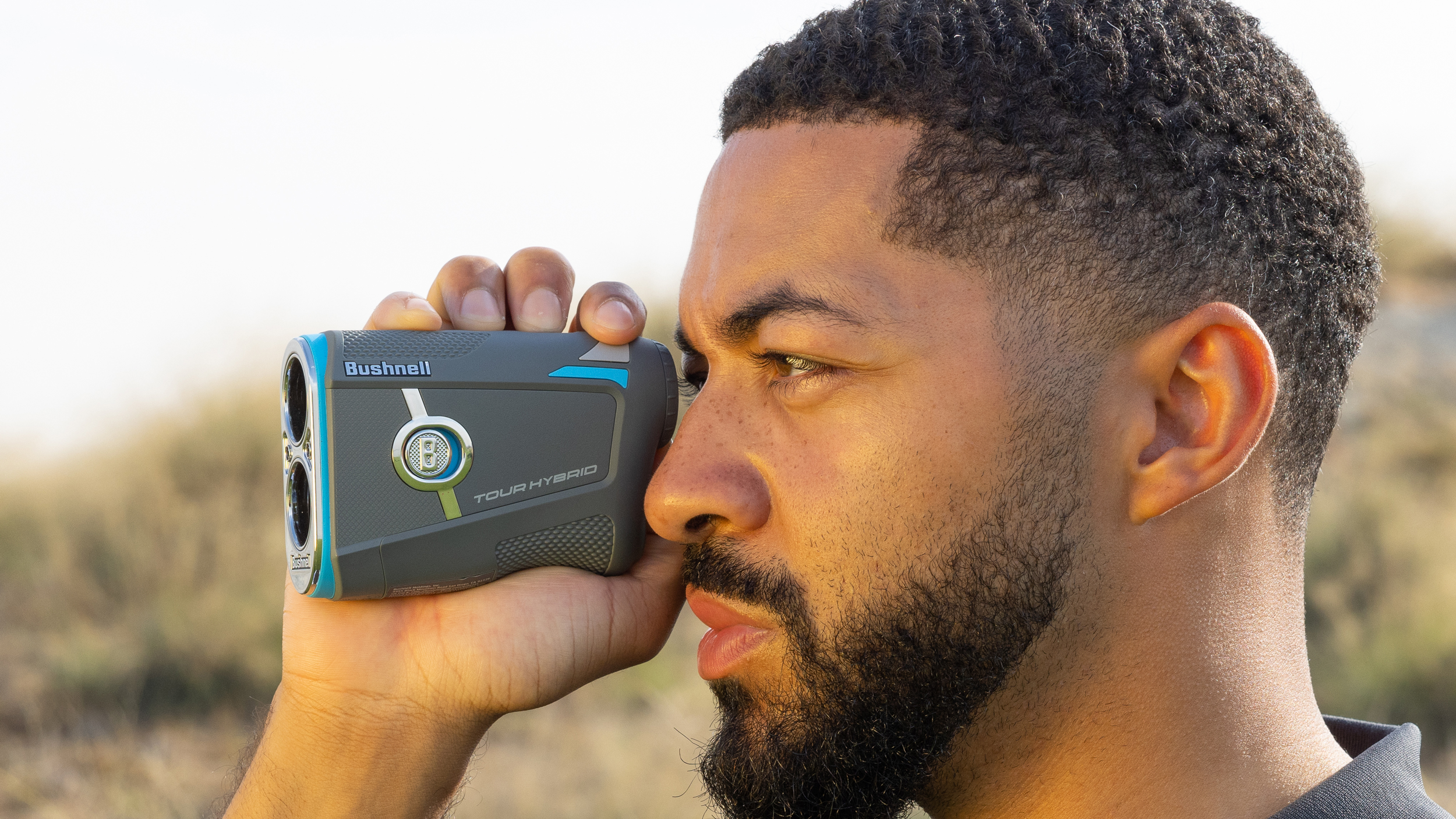 A golfer looks for a yardage using a Bushnell laser rangefinder